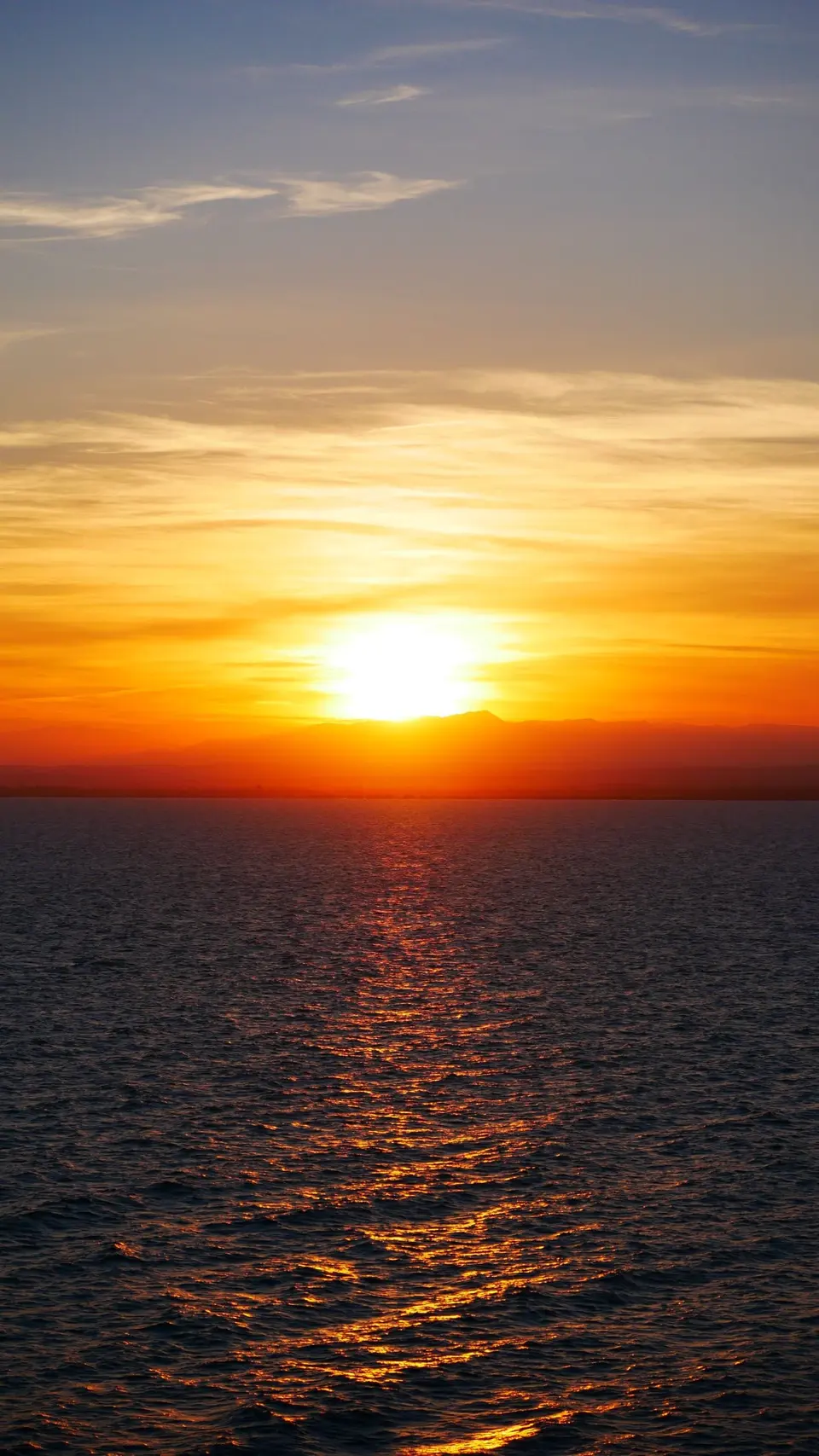 Sun breaking through clouds low over the sea, golden light on the water