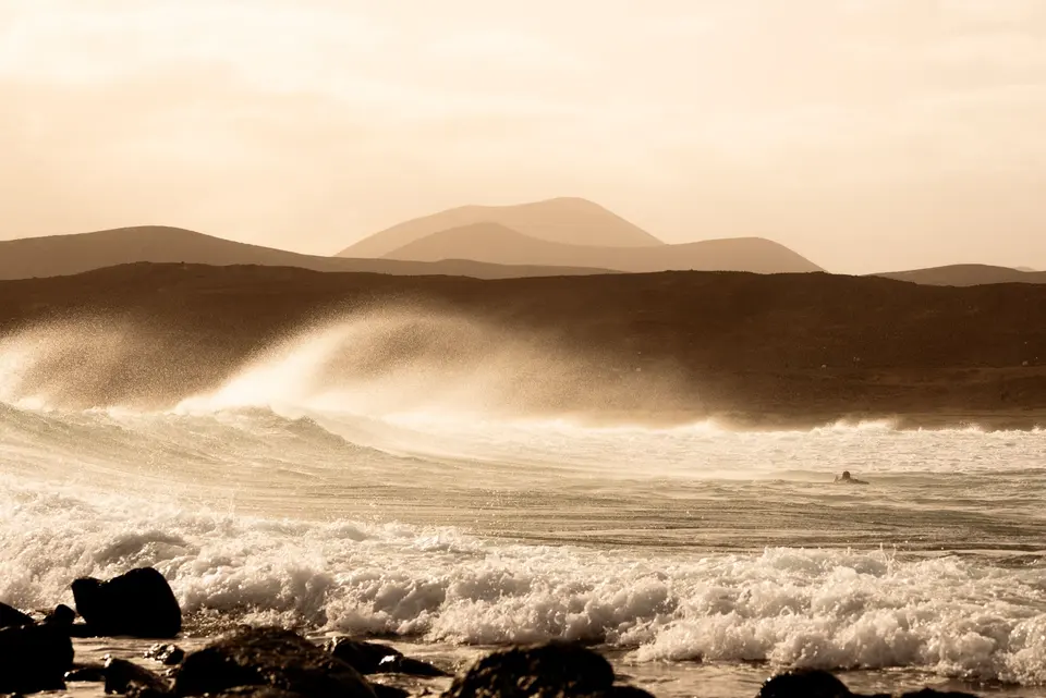 Ocean swell with wind-blown spray and volcanic mountains in the background, Lanzarote